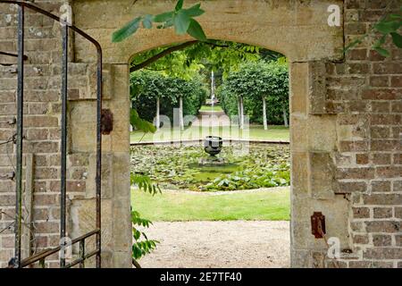 the view from an open gated doorway leads out to a fountain and a lily pond