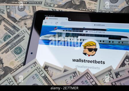 Wallstreetbets Reddit community web page seen on the tablet screen surrounded by US dollars. Concept for investment. Stafford, United Kingdom - Januar Stock Photo