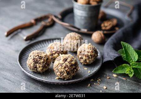 Dark chocolate truffle coated in chopped and toasted walnuts on a plate on stone background Stock Photo