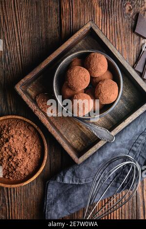 Delicious treat, homemade chocolate truffle covered in cocoa powder on rustic wooden background Stock Photo