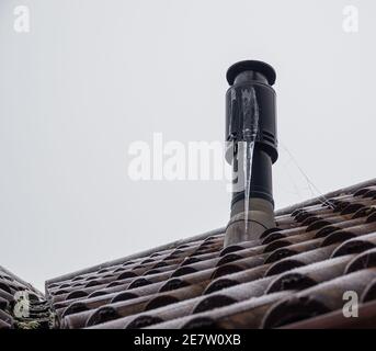 large icicle on the side of a boiler roof chimney Stock Photo