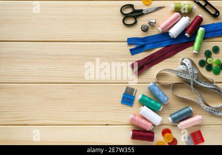 Flat lay of accessories for tailor. Set of sewing supplies on wooden background, space for text. Stock Photo