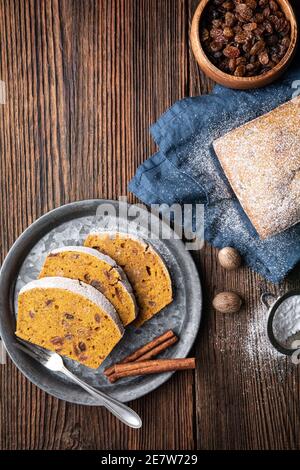Sweet whole grain pumpkin bread slices with raisins, sprinkled with powdered sugar on rustic wooden background Stock Photo