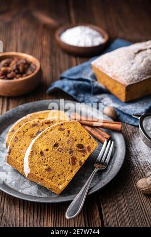 Sweet whole grain pumpkin bread slices with raisins, sprinkled with powdered sugar on rustic wooden background Stock Photo