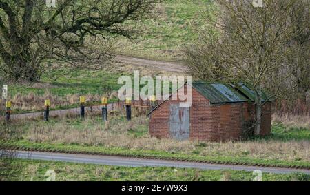 a tank crossing and road junction with a disused red brick building across the road on Salisbury Plain, Wiltshire Stock Photo