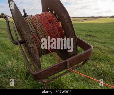 an old iron electric fence wire reel green fields backgound Stock