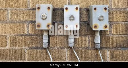 Three old utility boxes on an old brick wall. Stock Photo