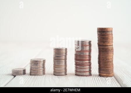 Stacks of coins are arranged by height on a light background. Side view with copy space. Stock Photo