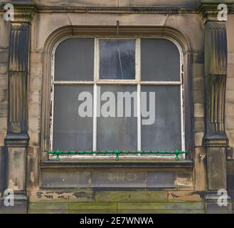 an old party arched window frame in an old sand stone building Stock Photo