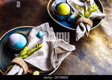 Easter table setting with colored eggs and boxwood leaves Stock Photo