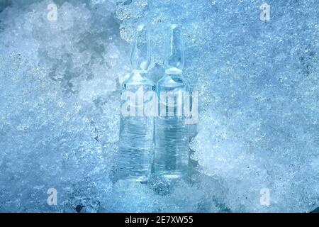 2 vaccine in glass ampoules with medical preparation for the treatment of covid viral disease is cooled to minus degrees in temperature lying on snow Stock Photo