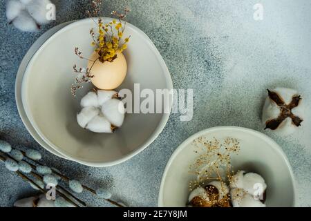 Minimalistic table setting for festive Easter dinner with white ceramic plates and bowl on white stone background Stock Photo