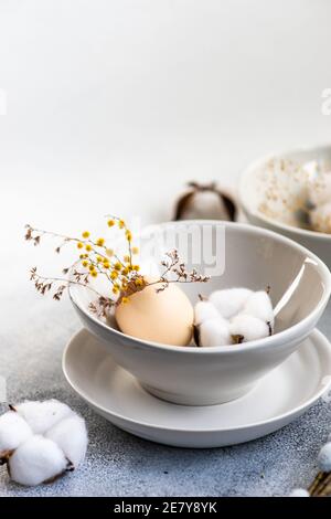 Minimalistic table setting for festive Easter dinner with white ceramic plates and bowl on white stone background Stock Photo