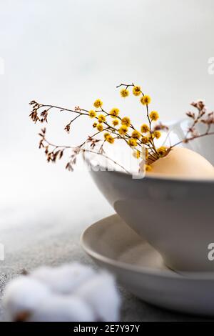 Minimalistic table setting for festive Easter dinner with white ceramic plates and bowl on white stone background Stock Photo