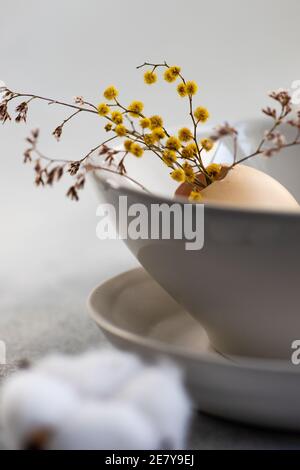 Minimalistic table setting for festive Easter dinner with white ceramic plates and bowl on white stone background Stock Photo