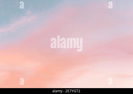 Background formed by a bright pastel authentic sky during sunset. Pink, peach, blue blur backdrop with empty space. Light color gradient transitions. Stock Photo
