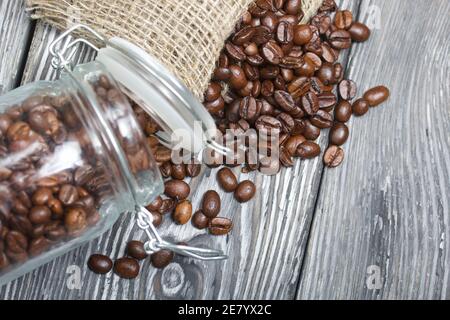 Coffee beans. Poured into a drag bag jar and linen bag. The bank is overturned. Close-up shot. Stock Photo