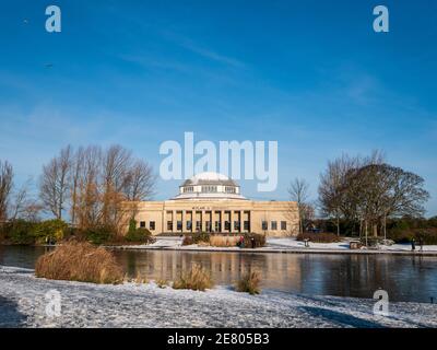 Wylam Brewery in the former Palace of Arts, Newcastle with snow and a blue cloudless sky and a lake in the fore. Few people just visible walking past. Stock Photo