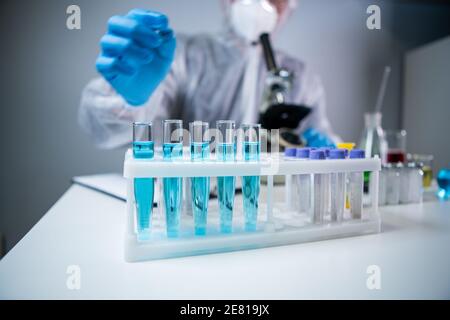 Close-up of scientists hand in blue latex gloves examines samples chemical liquid in test tube in science laboratory. Research and development. Lab Stock Photo