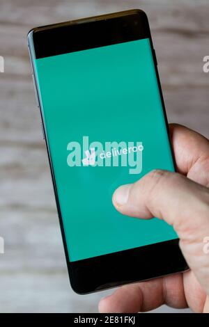 A hand holding a mobile phone or cell phone with the deliveroo app open on screen Stock Photo