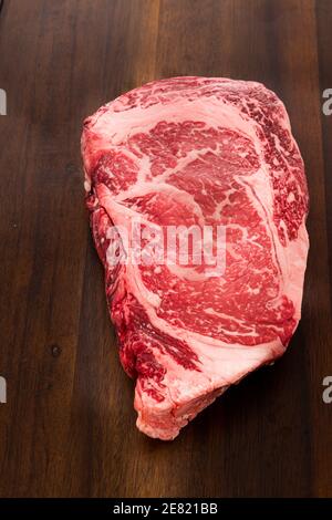 A raw New York strip Ribeye steak thick steak on a cutting board. Stock Photo