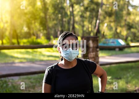 Close-up portrait of a beautiful black lady wearing a disposable mask and dark glasses Stock Photo