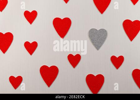 Silver Heart Amongst Red Hearts On Textured White Stock Photo