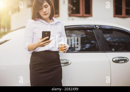 Business woman hand holding a coffee cup to take away and watching the plans on the smartphone Stock Photo