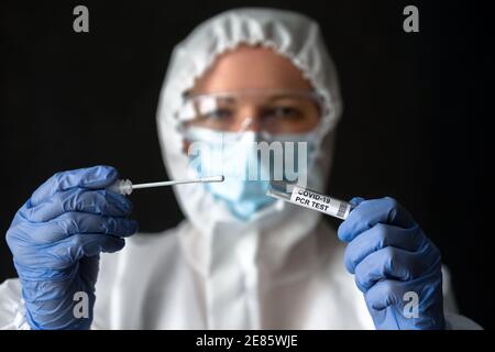 COVID-19 swab collection kit in doctor’s hand, nurse in medical PPE suit holds tube of coronavirus PCR test. Concept of corona virus diagnostics, test Stock Photo