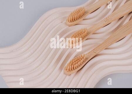 Trendy still life composition with natural bamboo toothbrushes on wavy plaster mold background with copy space. Sustainable lifestyle, zero waste home Stock Photo