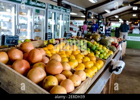 Display of fruit at a local farmers' market with out-of-focus shoppers in the background Stock Photo