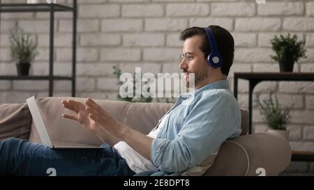 Side view man wearing headphones using laptop, making video call Stock Photo