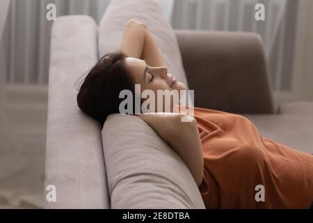 Close up peaceful young woman leaning back on cozy couch Stock Photo
