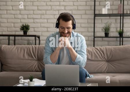 Smiling man wearing headphones watching webinar, studying at home Stock Photo
