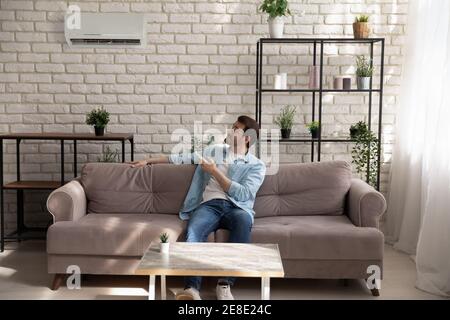 Full length man wearing glasses using air conditioner remote controller Stock Photo