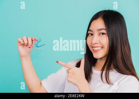 Portrait young Asian beautiful woman smiling pointing with finger silicone orthodontic retainers for teeth, Female hold teeth retaining tools after re Stock Photo