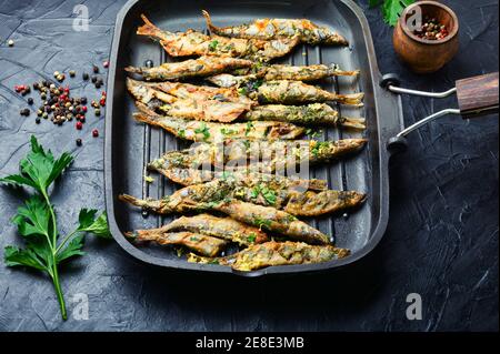 Fried capelin garnished with parsley and lemon zest in a pan Stock Photo