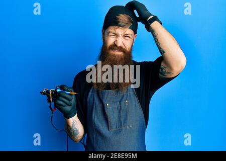 Redhead man with long beard tattoo artist wearing professional uniform and gloves confuse and wondering about question. uncertain with doubt, thinking Stock Photo