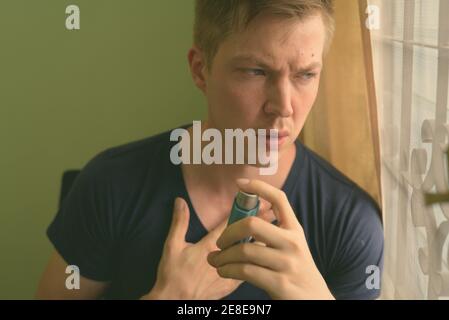 Young handsome man using asthma inhaler at home Stock Photo