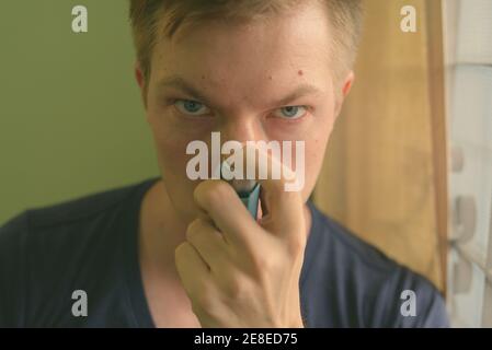 Young handsome man using asthma inhaler at home Stock Photo