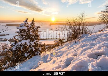 Beautiful sunset over snowy winter landscape in the Swabian Alps with trees in the foreground Stock Photo