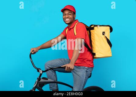 Smiling delivery delivery man riding bicycle at studio Stock Photo