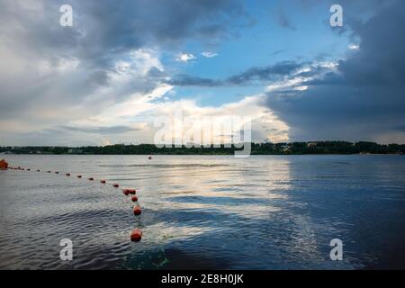 Buoys line the safe swimming area on the river on a summer evening Stock Photo