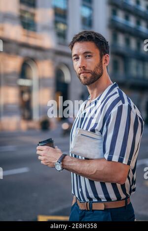 Young stylish man having takeaway coffee while walking around barcelona Stock Photo