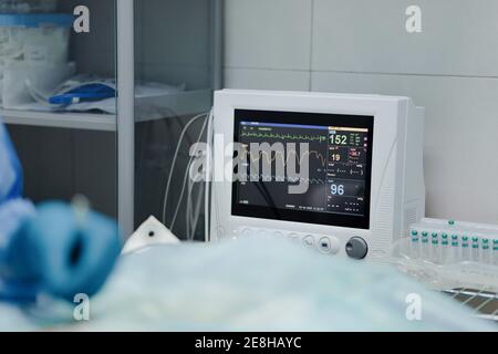 Crop anonymous veterinarian in sterile gloves operating animal near EKG test monitor in hospital Stock Photo