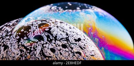 Panoramic view of closeup bubble textured backdrop representing colorful planets with wavy lines on round shaped surface on black background Stock Photo