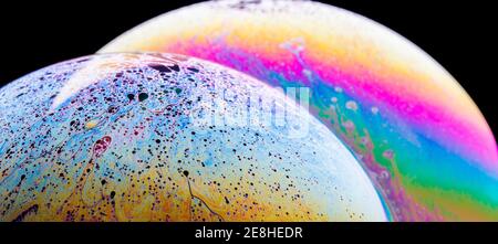 Panoramic view of closeup bubble textured backdrop representing colorful planets with wavy lines on round shaped surface on black background Stock Photo