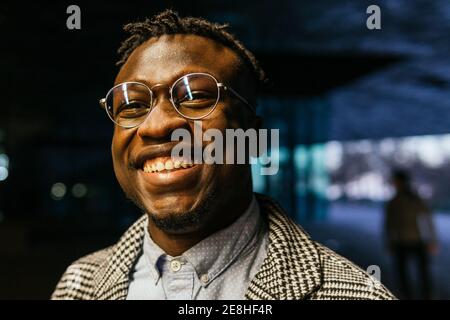 Portrait of happy young African American male office employee while looking at camera in town at dusk Stock Photo