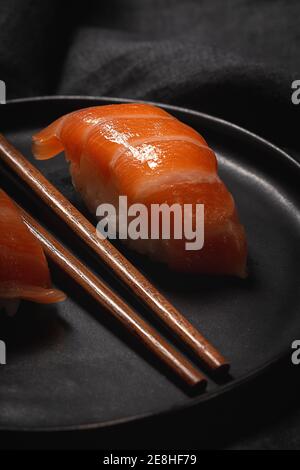 Top view composition of delicious fresh sushi and bamboo chopsticks served on black platter on checkered cloth Stock Photo