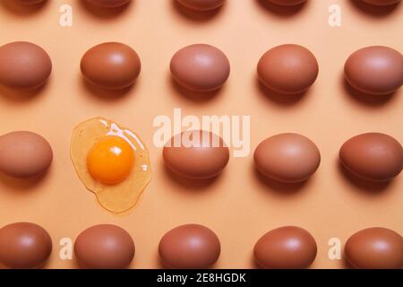 From above of pattern of whole brown eggs placed in even rows with raw eggs on peach table in studio Stock Photo